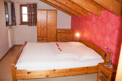 a bedroom with a wooden bed with a red wall at Gastreinhof in Meltina