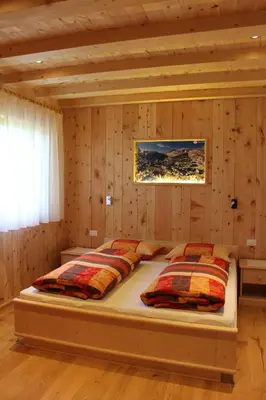 a bedroom with a bed in a wooden wall at B&B Ciasa Brüscia in San Vigilio Di Marebbe