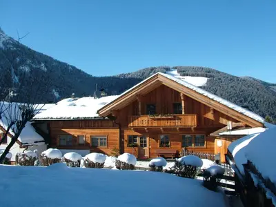 a large wooden building with snow on the ground at B&B Ciasa Brüscia in San Vigilio Di Marebbe