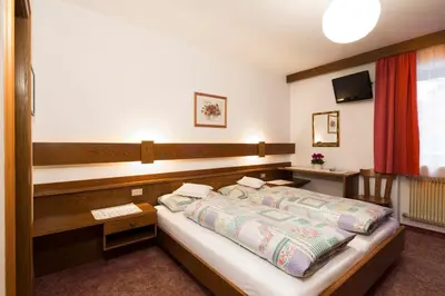 a bedroom with a bed and a desk and a television at Ciasa Iris in Colfosco