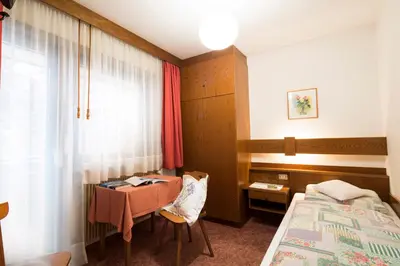 a bedroom with a bed and a table and a window at Ciasa Iris in Colfosco