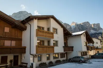a building with wooden balconies and mountains in the background at Ciasa Iris in Colfosco