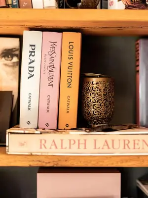 a book shelf with books and a cup on it at Sportony Mountain Lodges in La Villa