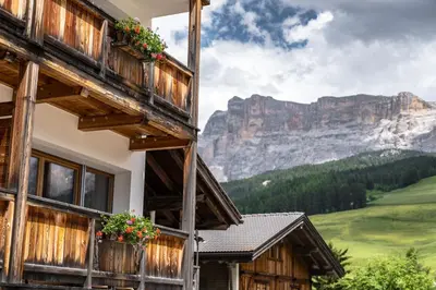 a building with flowers on the balconies with mountains in the background at Ciasa Agreiter in La Villa