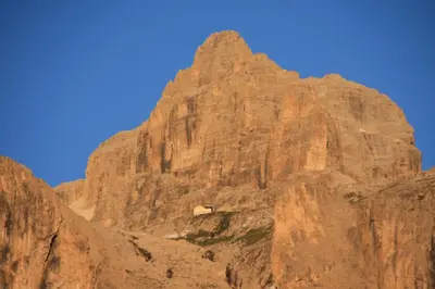 a large brown mountain with a small building on it at Apartments Residence Alta Badia in Colfosco
