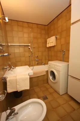 a bathroom with a toilet sink and a washing machine at Apartments Residence Alta Badia in Colfosco