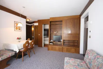 a living room with a table and a couch and a television at Apartments Residence Alta Badia in Colfosco