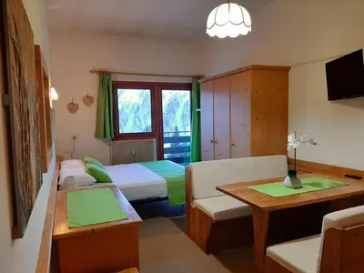 a small room with two beds and a table at Casa AQ27 sulle piste da sci in Falcade