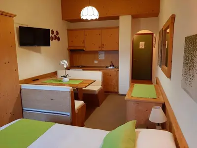 a small room with a kitchen with a table and a kitchen at Casa AQ27 sulle piste da sci in Falcade