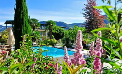 a garden with a swimming pool and purple flowers at Apparthotel Gartenresidence Nalserhof in Nalles