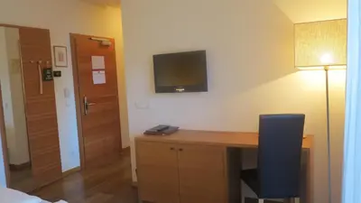 a room with a desk with a television on the wall at Apparthotel Gartenresidence Nalserhof in Nalles