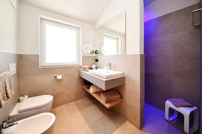a bathroom with a sink and a toilet and a window at Apparthotel Gartenresidence Nalserhof in Nalles