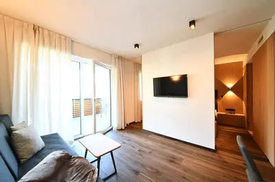 a living room with a couch and a tv on a wall at Apparthotel Gartenresidence Nalserhof in Nalles