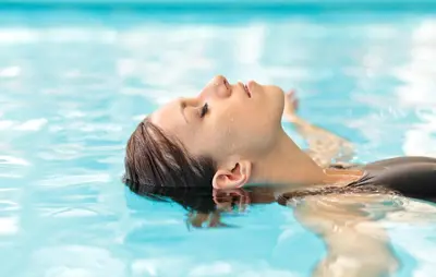 a woman laying in the water in a swimming pool at Hotel Brückenwirt - Al Ponte in Montagna
