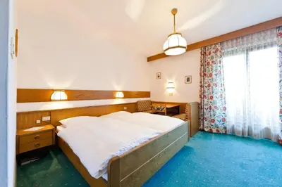 a bedroom with a large bed and a window at Hotel Brückenwirt - Al Ponte in Montagna