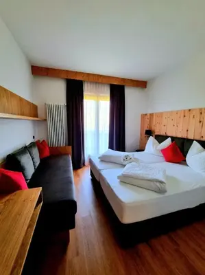 a hotel room with two beds and a couch at Hotel Brückenwirt - Al Ponte in Montagna