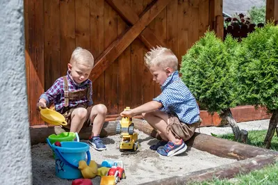 two young boys playing with toys in a sandbox at Sigmundhof in Bressanone