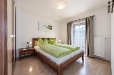 a bedroom with a bed with green sheets and a window at Sigmundhof in Bressanone