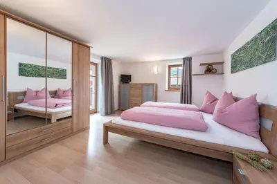 a bedroom with a large bed with pink pillows at Sigmundhof in Bressanone