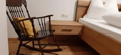 a black rocking chair sitting next to a bed at Residence Maximilian in Vipiteno