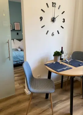 a dining room with a table and a clock on the wall at Galilei Apartment in Merano