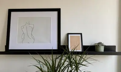 a black shelf with a picture and a plant on it at Galilei Apartment in Merano