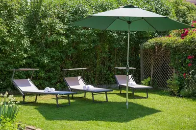 two chairs and an umbrella in the grass at Hotel B&B Martha in Brunico