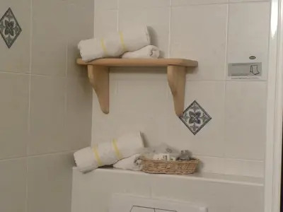 a bathroom with a shelf with towels and a basket at Hotel B&B Martha in Brunico