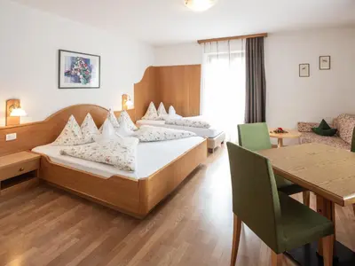 a hotel room with two beds and a table at Hotel B&B Martha in Brunico