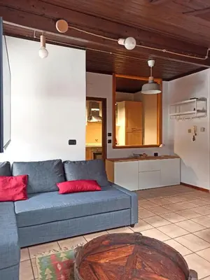 a living room with a blue couch and a kitchen at Mansarda Marmolada Canazei, parking, ski slopes 300m in Alba di Canazei