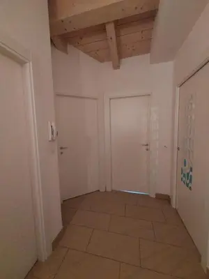 an empty hallway with white walls and a wooden ceiling at Appartamento Al Borgo in Cles