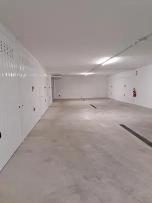 an empty parking garage with white walls and concrete floors at Appartamento Al Borgo in Cles