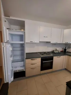 a kitchen with white cabinets and an open refrigerator at Appartamento Al Borgo in Cles