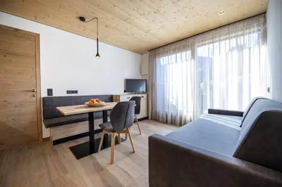 a room with a bed and a table and a couch at Apartments Dami in Ortisei