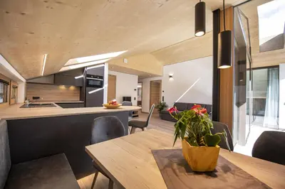 a kitchen and dining room with a wooden table and chairs at Apartments Dami in Ortisei