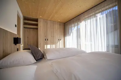 a bedroom with two white beds and a window at Apartments Dami in Ortisei