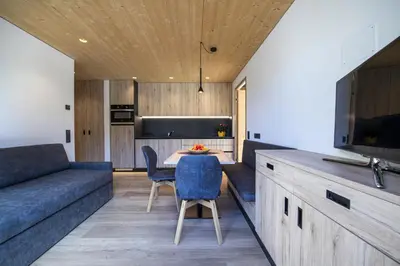 a kitchen and living room with a table and a couch at Apartments Dami in Ortisei