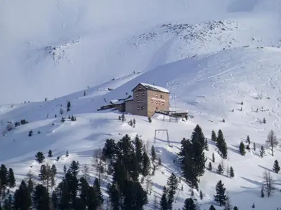 a building on top of a snow covered mountain at Ladurner Home in Brunico