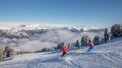 a group of three people skiing down a snow covered slope at Residence Casa Cavalese in Cavalese