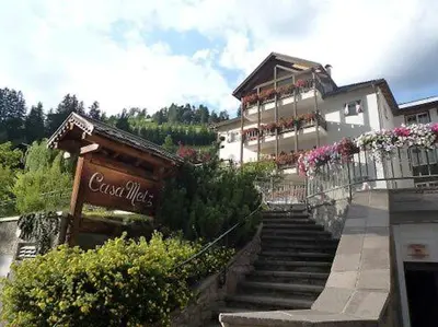 a building with stairs leading up to a building with flowers at Groden Apartments in Santa Cristina in Val Gardena