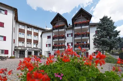 a building with red flowers in front of it at Groden Apartments in Santa Cristina in Val Gardena