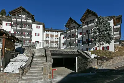 a building with a garage and stairs in front of it at Groden Apartments in Santa Cristina in Val Gardena