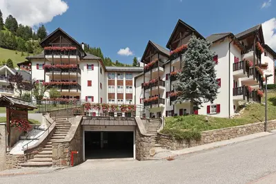 a large white building with a tree in front of it at Groden Apartments in Santa Cristina in Val Gardena