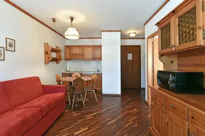 a living room with a red couch and a table at Groden Apartments in Santa Cristina in Val Gardena