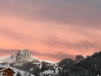 a sunset in the mountains with a snow covered mountain at Apartments Mezdi in Santa Cristina in Val Gardena
