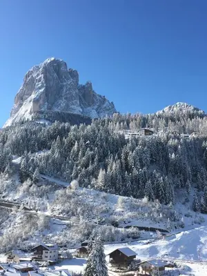 a snow covered mountain with a village in front of it at Apartments Mezdi in Santa Cristina in Val Gardena