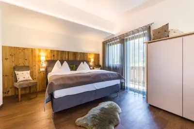 a hotel room with a bed and a chair at Apartments Mezdi in Santa Cristina in Val Gardena
