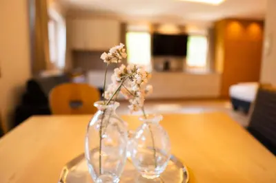 two clear glass vases with flowers in them on a table at Anewandterhof in Brunico