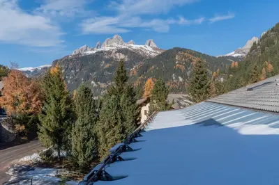 a snow covered roof of a building with a mountain at Casa Val di Fassa in Canazei