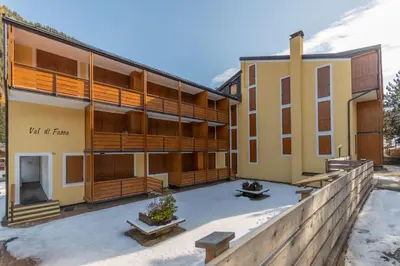 an apartment building with a courtyard in the snow at Casa Val di Fassa in Canazei